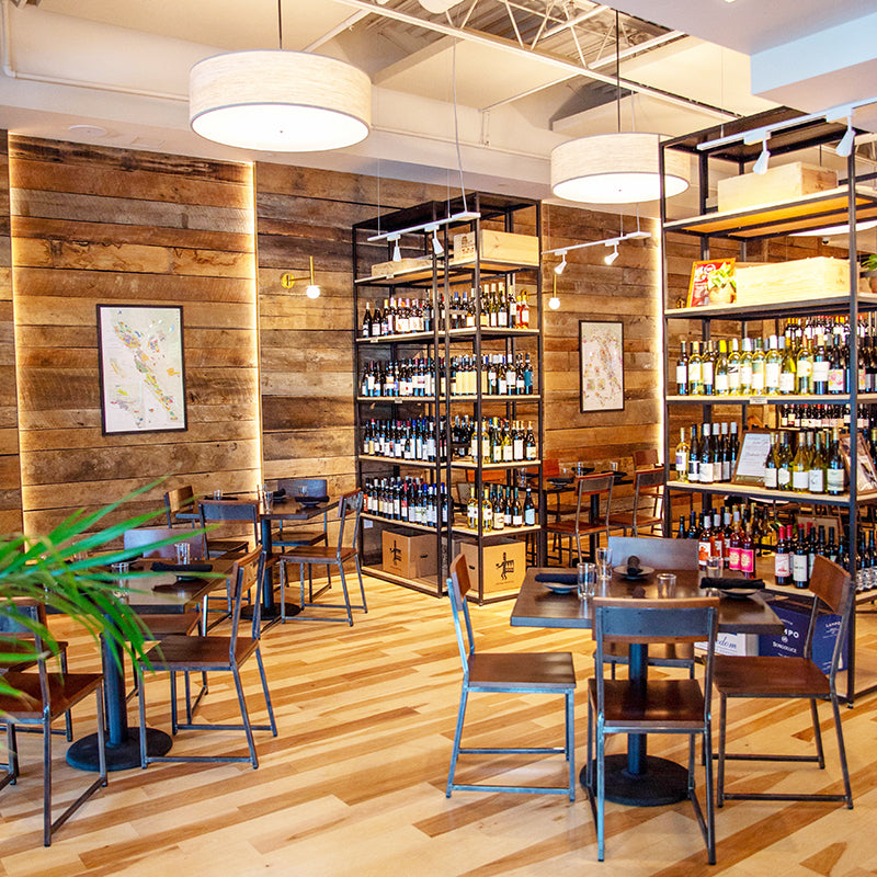 The dining room at Foxcroft Raleigh has wooden shelves, tables, and chairs.