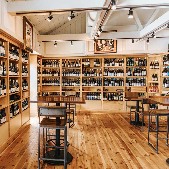 The interior of Foxcroft SouthPark with tall wine shelves and high top tables and chairs.