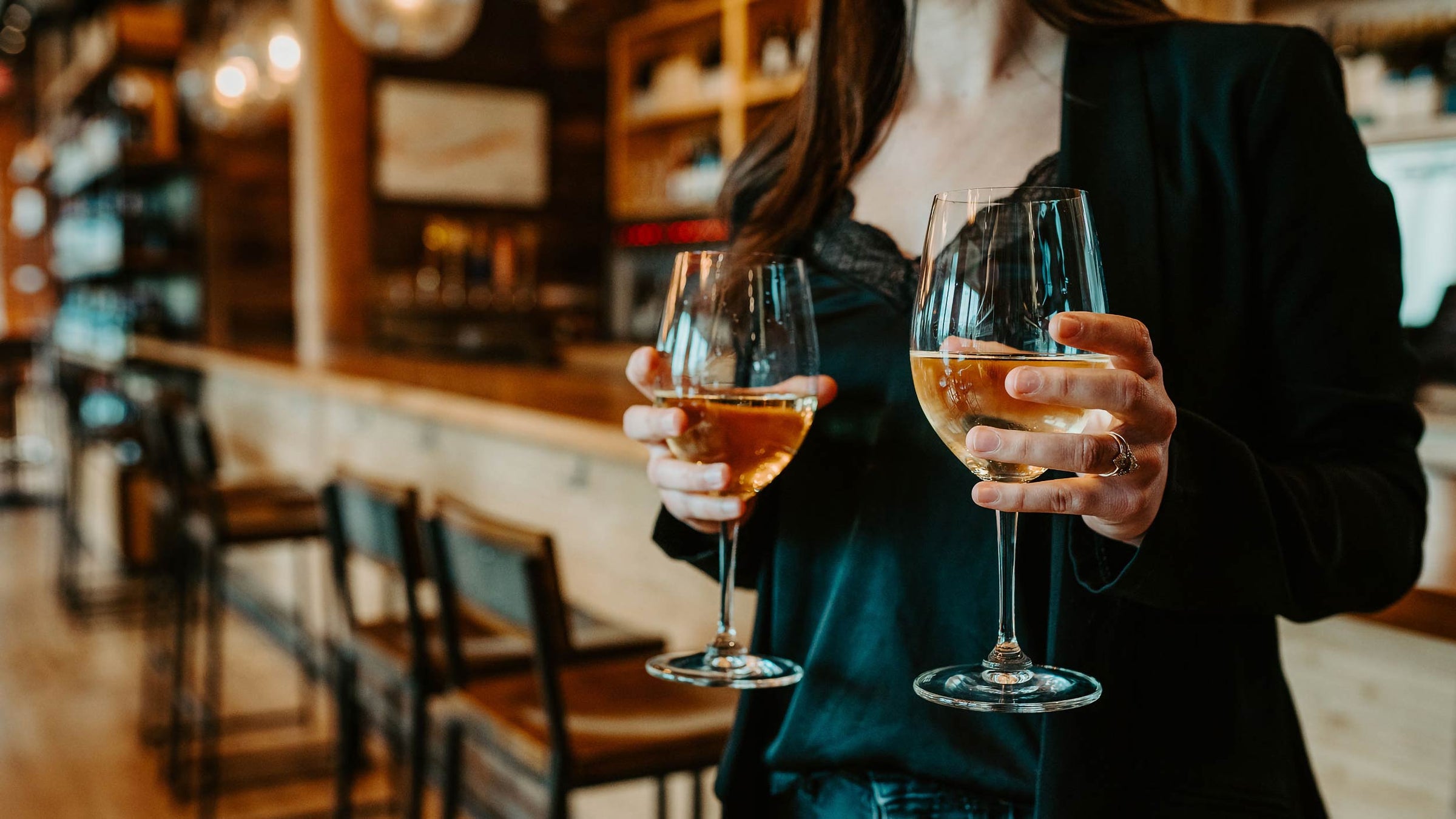 Server holding two glasses of white wine
