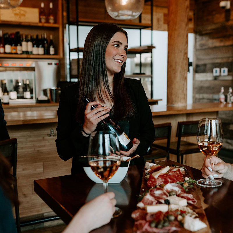 Server displaying the bottle of sparkling rose that she poured the seated guests
