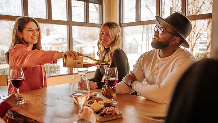 Tasting host pouring red wine for a customer at the table