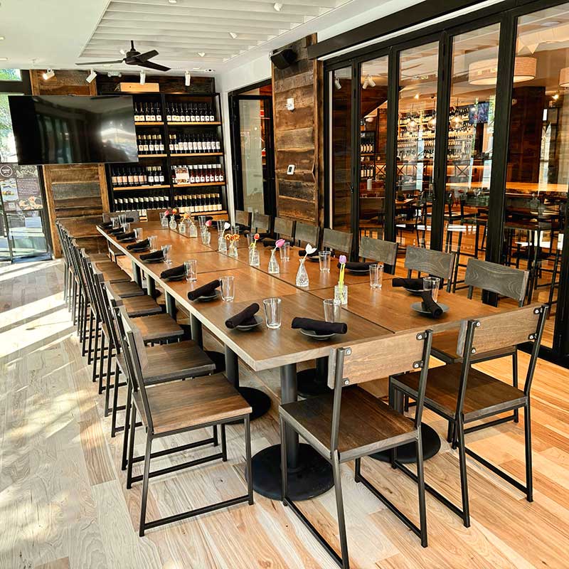 Dining room lined with glass walls and a long table setup for an event. A tv for presentations is in the background.