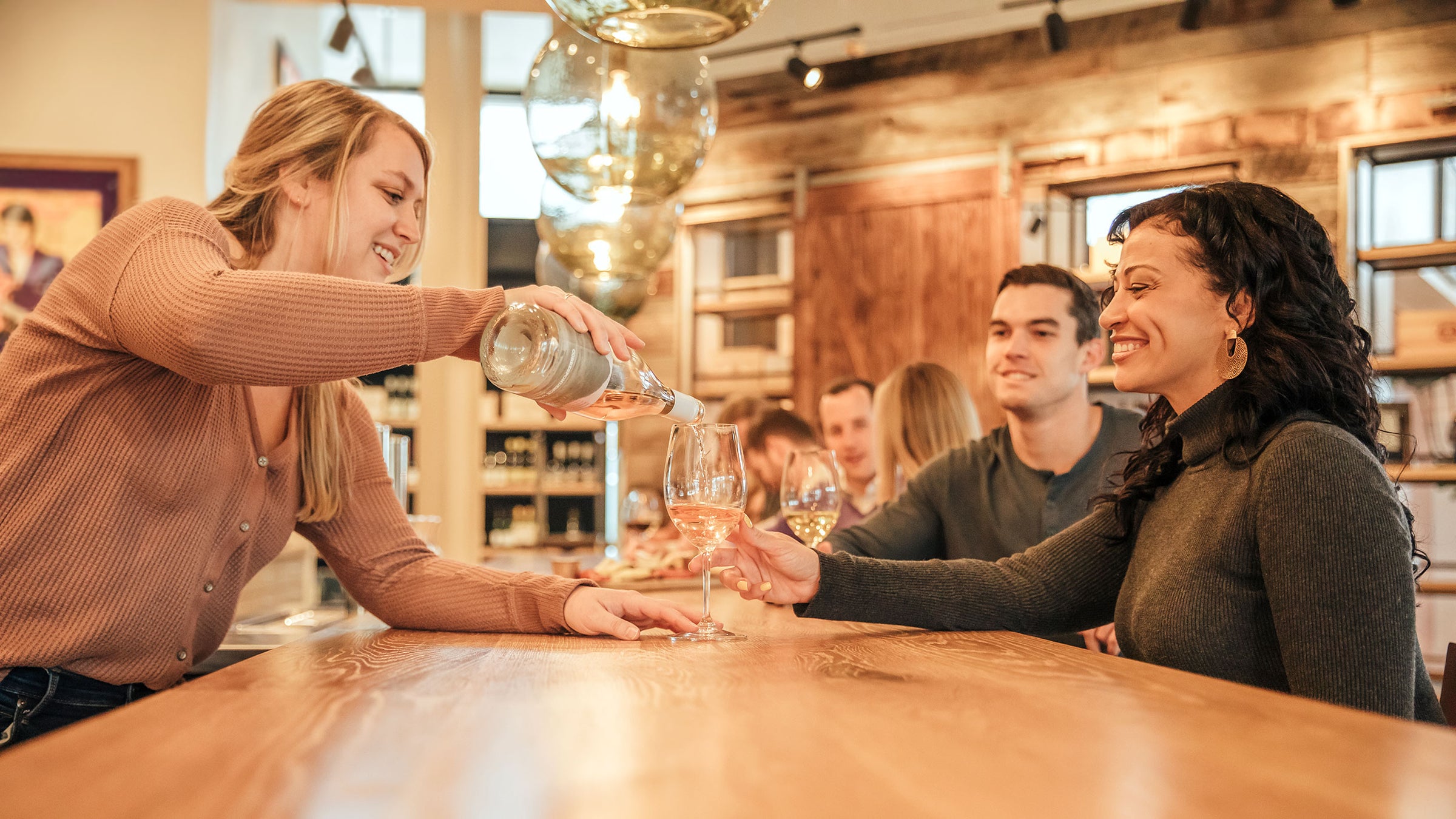 Woman pouring wine into another woman's glass.