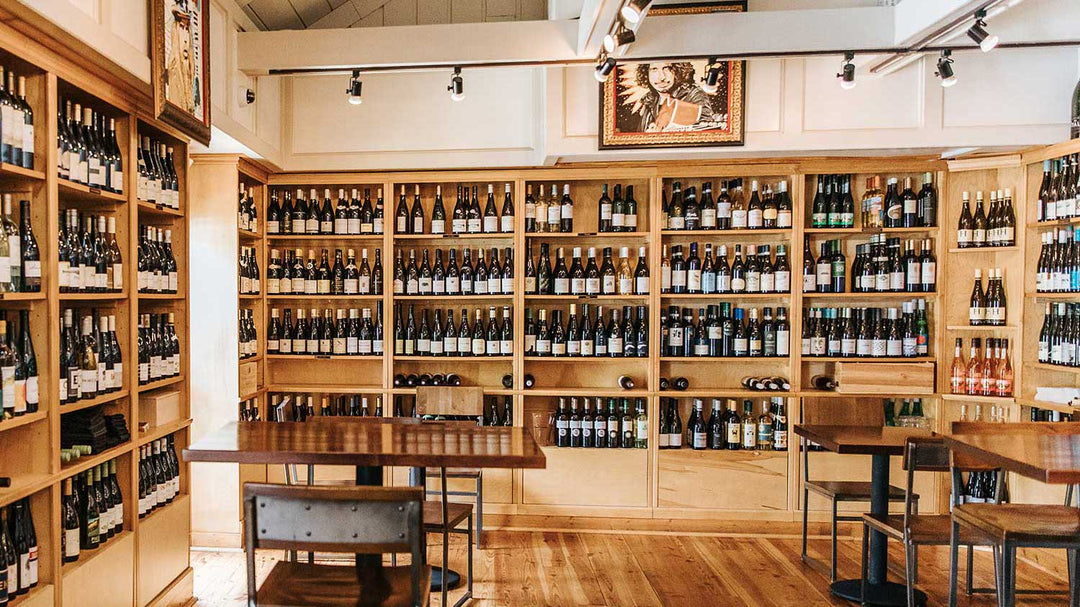 Inside Foxcroft SouthPark's restaurant with wood tables and tall wine shelves