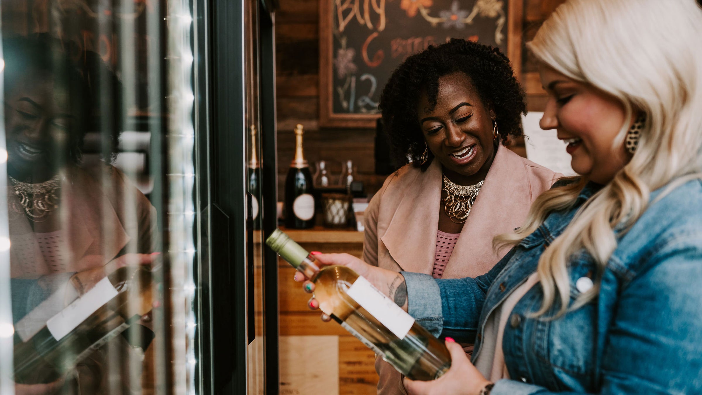 Sommelier recommending a bottle of wine to a customer in front of the wine shop fridge